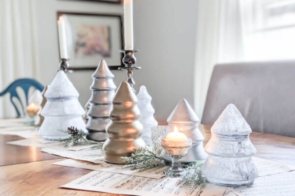 Simple DIY Christmas tablescape of snowy, silver, and gold glass Christmas trees and silver candlesticks.