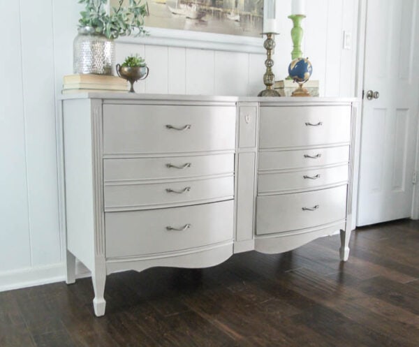 wooden dresser painted greige against white wall.