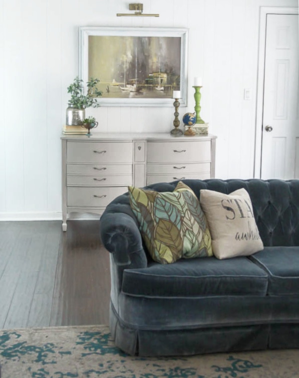 painted dresser against wall with couch in front.