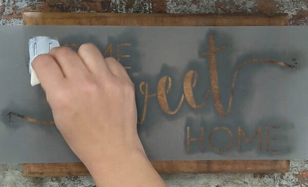 using a sponge to apply paint to wood sign