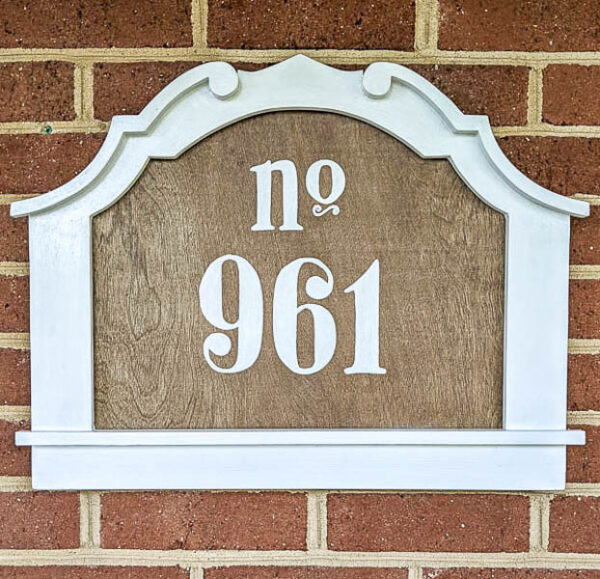 diy address sign made from an upcycled frame and plywood hanging on brick