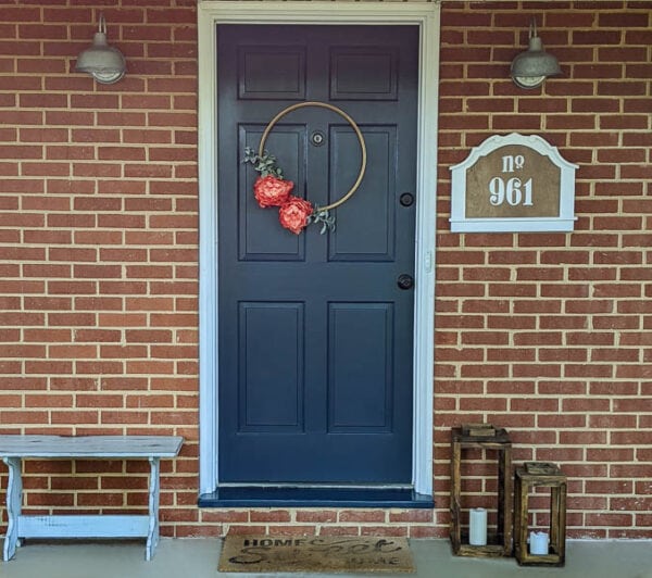 front porch of brick ranch home with navy front door, diy house number, and embroidery hoop wreath