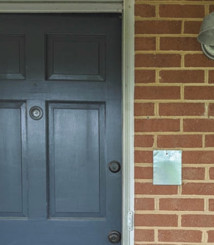 brick house with blue front door and hole where old speaker was