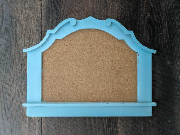 blue framed corkboard with an interesting arched shape