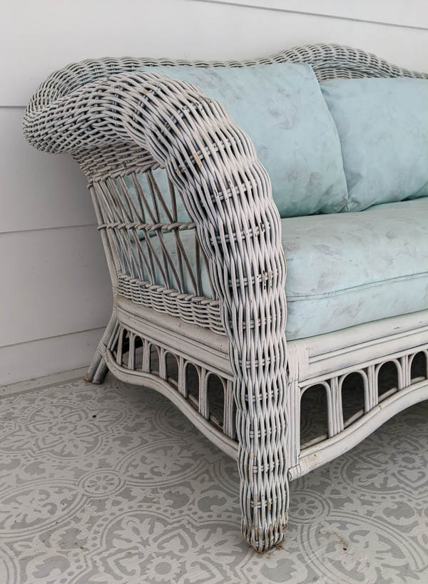 close up of white wicker sofa with dingy, peeling paint