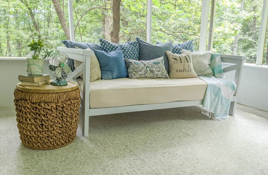 daybed filled with pillows and a throw blanket with a woven basket table next to it.