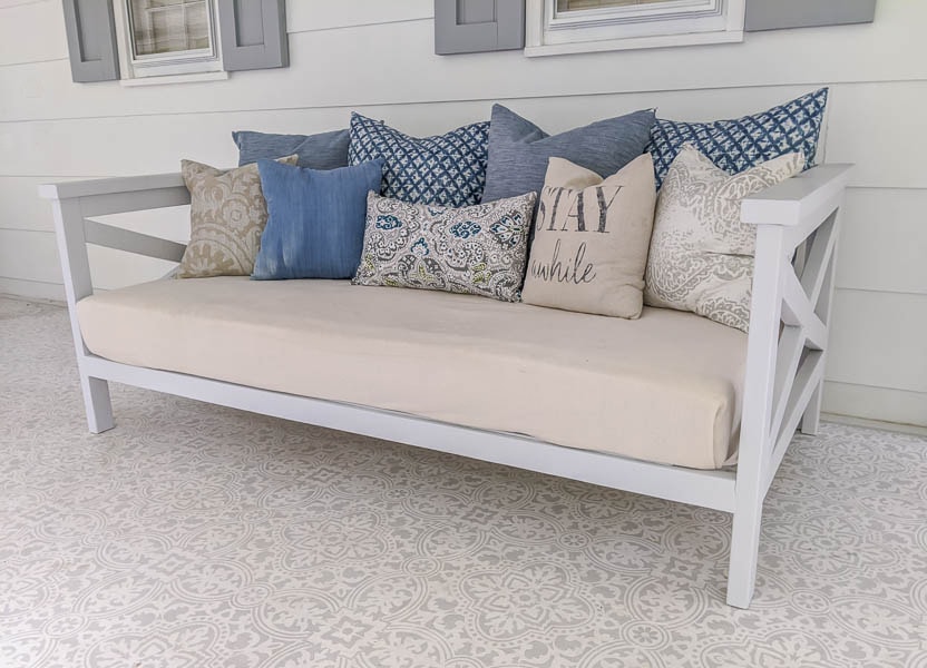 completed daybed with mattress in linen cover and blue and tan pillows.
