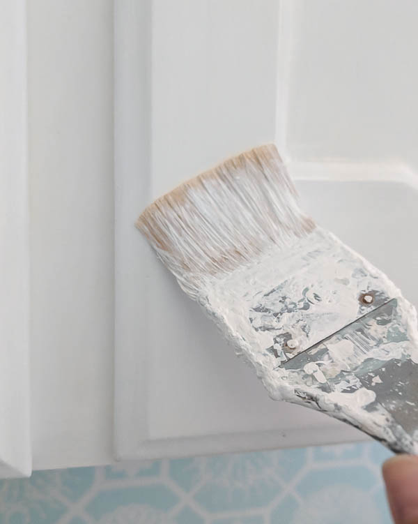 touching up cabinet paint with a small paintbrush