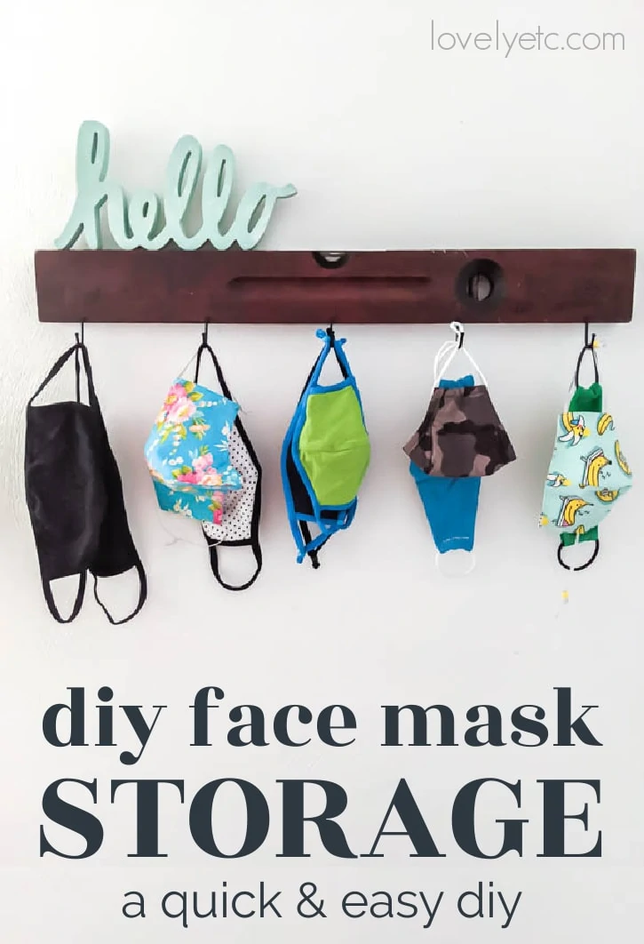 face masks for the whole family stored on wall hooks next to the front door with a cute hello sign above