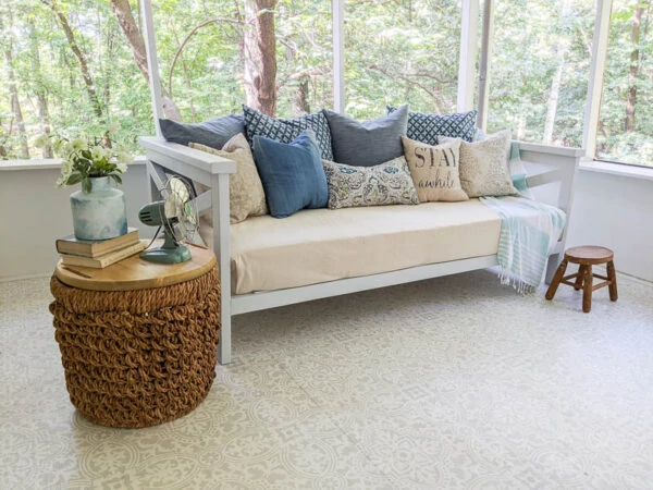 diy wood daybed on porch with drop cloth cover and lots of pillows