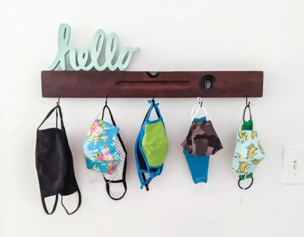 wall hook mask organizer with masks of different sizes hanging from the hooks