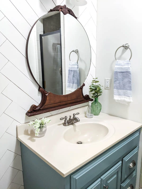 Painted blue vanity and vintage wood mirror against white wood wall