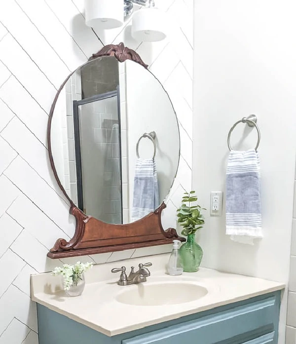 Large round vintage mirror from an old dresser hangs above the painted bathroom vanity.