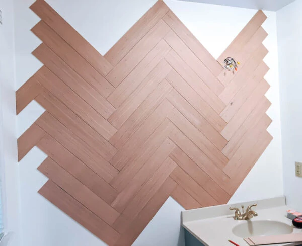 partially finished herringbone wood wall with empty spaces all along the edges where wood hasn't been added yet.
