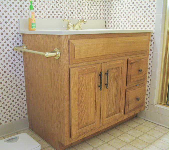 basic oak bathroom vanity with shiny gold faucet and old brass hardware