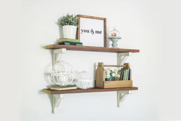 diy wood shelves with white wood shelf brackets decorated with a sign, plants, books, and other nick knacks
