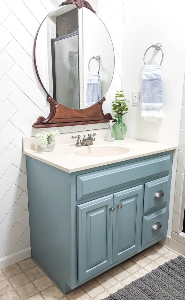 bathroom makeover with the bathroom vanity painted blue, new brushed nickel hardware, a vintage wood mirror, and a wood accent wall