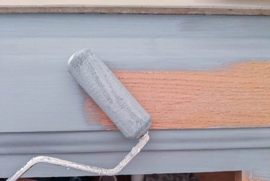 using a small foam roller to paint a bathroom cabinet light blue