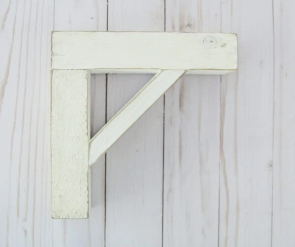 wood shelf brackets with a weathered white paint finish.