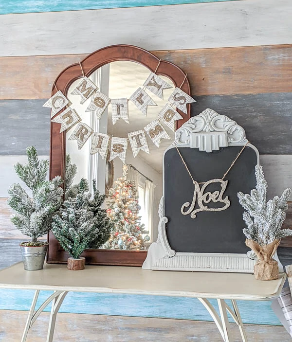 Entryway table with glittery Merry Christmas banner and mini Christmas trees.