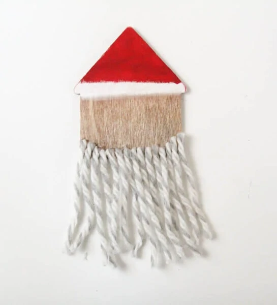 DIY wooden santa ornament with yarn beard glued along bottom.