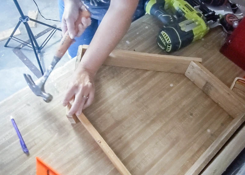 Attaching the roof to the diy wood nativity using a hammer and nails.