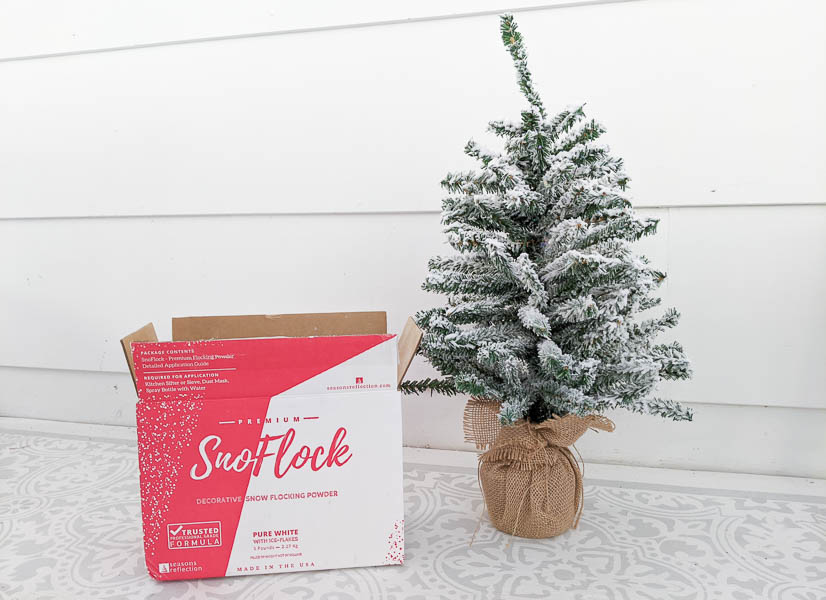 Small Christmas tree next to a box of SnoFlock flocking powder.