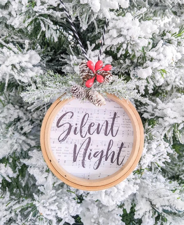 Silent Night embroidery hoop Christmas ornament hanging on flocked Christmas tree.