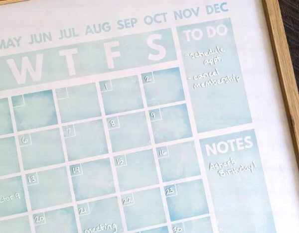 light blue calendar with dates and notes written with a white chalk marker.