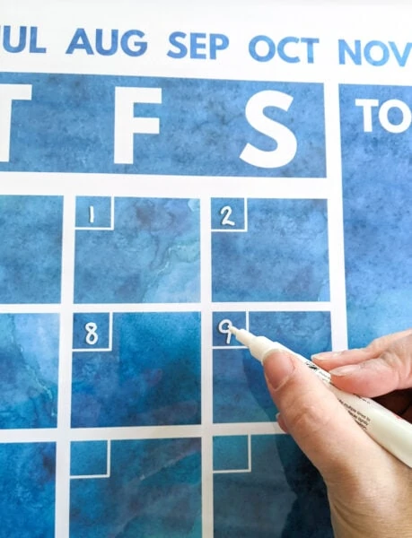 writing on dark blue calendar with a white chalk marker.