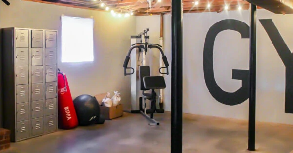 basement gym with large open space, punching bag, lockers, and weight machine.