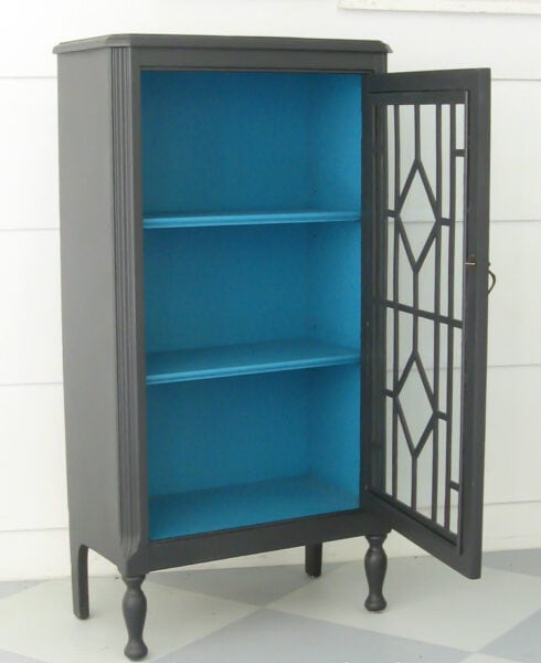 small cabinet painted charcoal gray with a pop of turquoise inside.