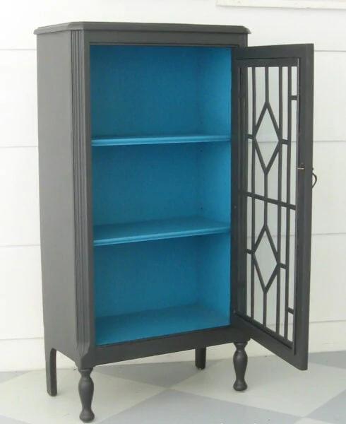 small cabinet painted charcoal gray with a pop of turquoise inside.