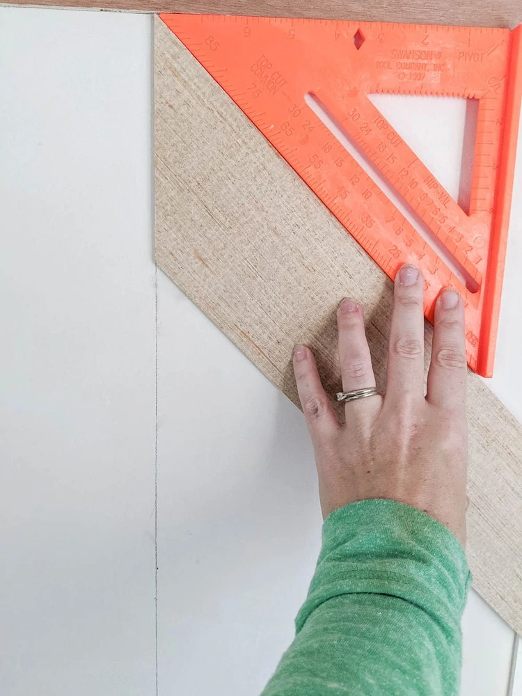 using a speed square to double check the angle on the first wood plank.