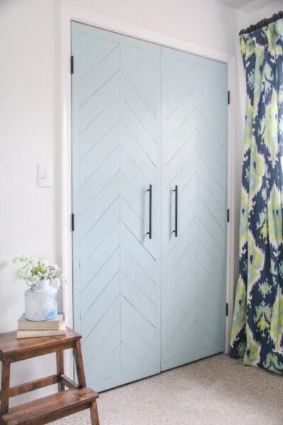 sliding closet doors updated to hinged doors with a modern blue herringbone wood plank design.