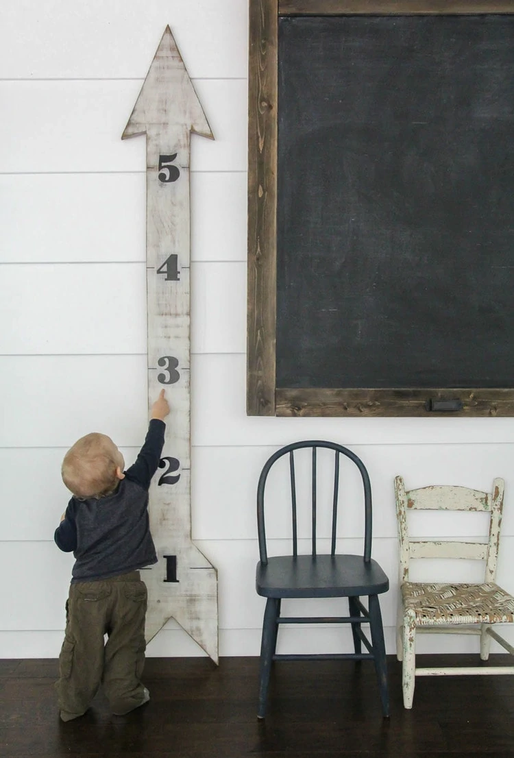 toddler standing next to diy wood growth chart.