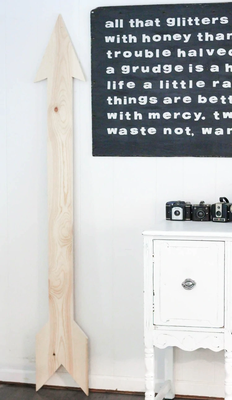 large wooden arrow leaning against the wall before painting.