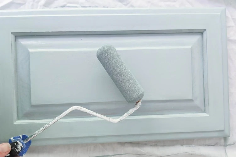 paint roller and cabinet door painted blue.