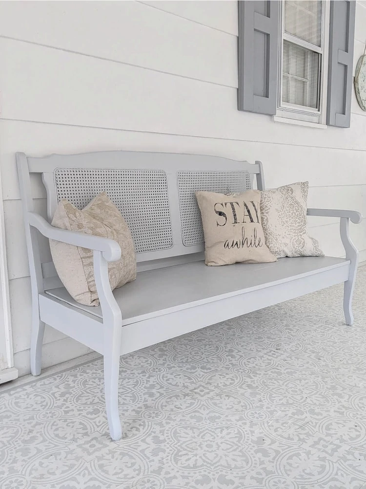 Completed bench with wooden seat and light gray exterior paint on porch.