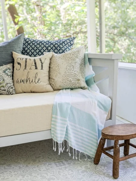 wooden daybed on porch with cover and pillows protected with waterproofing spray.