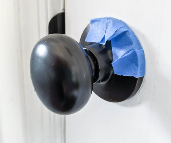 taping around a door knob with small pieces of painter's tape.