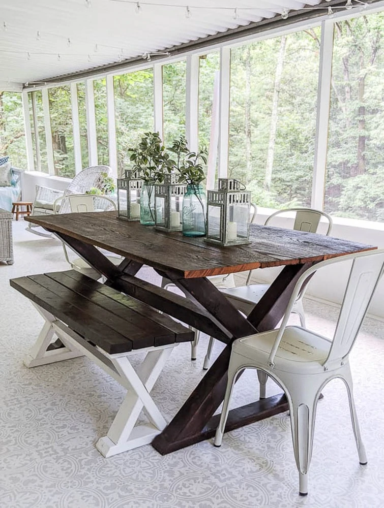 finished bench with DIY farmhouse table and metal chairs on screened-in porch.