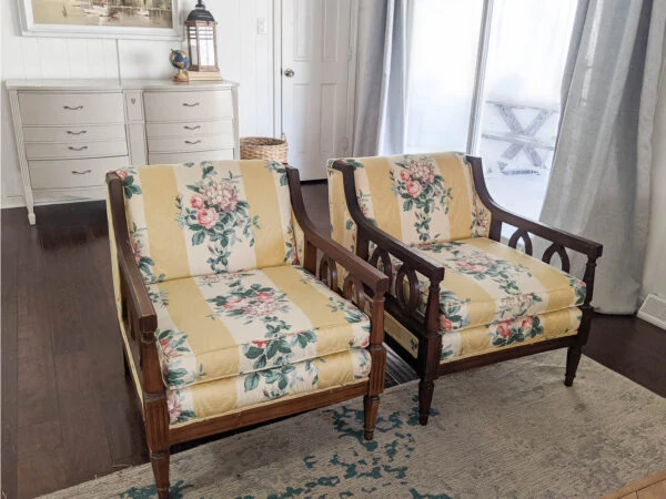 Vintage chairs with wooden arms and yellow floral fabric ready for reupholstery.