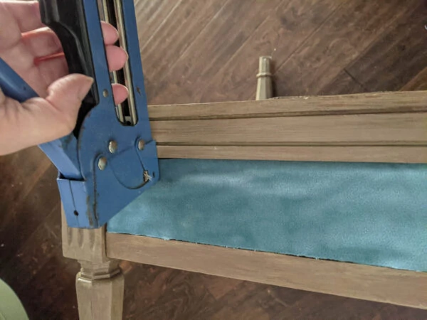 Stapling fabric along the arms of the chair using a staple gun.