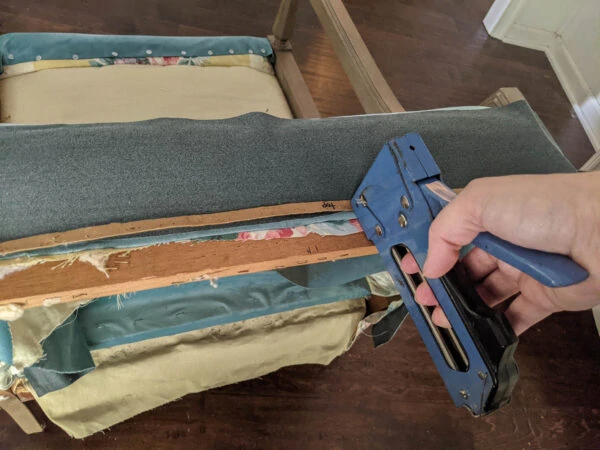 Stapling a cardboard strip onto the chair for a clean upholstery line.