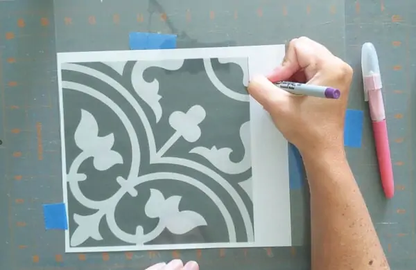 Using a super fine tip Sharpie to trace a patterned tile design onto a stencil blank.