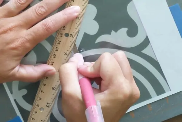 Using a ruler to cut straight lines when cutting out a stencil.