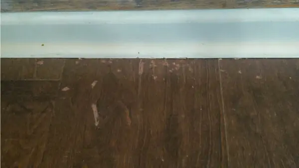 Using wax fill stick to fill scratches on wood floor.
