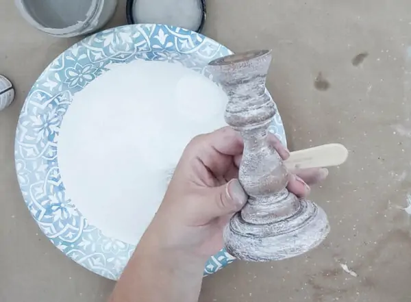 Wooden candlestick after dry brushing white paint onto it.