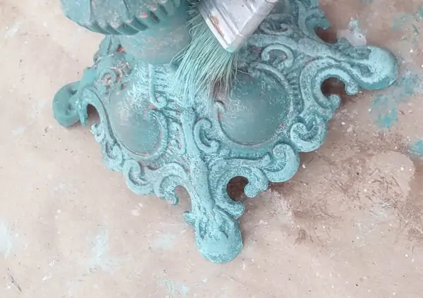 Dry brushing the light blue-green paint onto the surface.